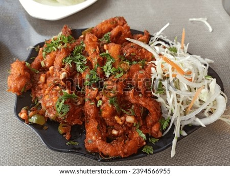 A close up picture of a Spicy baby corn manchurian served with vegetables in a restaurant in India.
