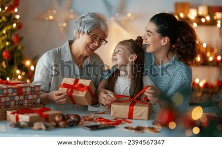 Happy Holidays. Cheerful grandmother, mother and cute daughter girl preparing for Christmas. People wrapping gifts, decorating home. Loving family with presents in room.