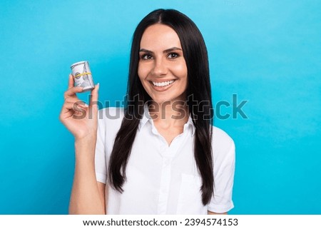 Photo of adorable cheerful girl dressed white shirt rising cash money roll isolated blue color background