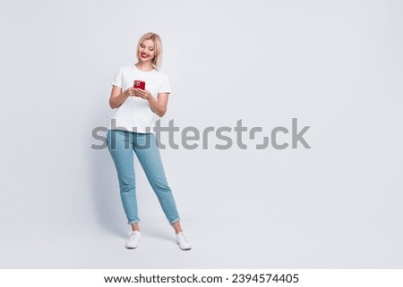 Full size photo of smart girl with bob hairdo dressed white t-shirt hold smartphone near empty space isolated on gray color background