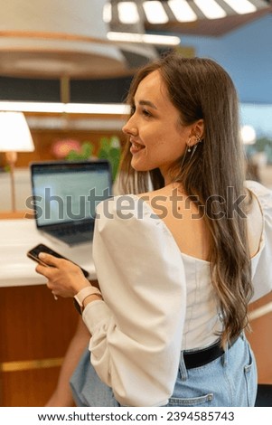 Young woman employee wearing wide-sleeved blouse smiles during photosession. Coworker enjoys photoshoot at coworking premise during work Royalty-Free Stock Photo #2394585743