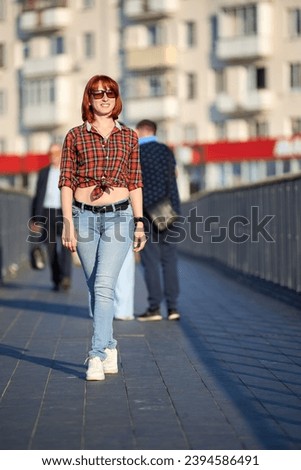 A fashionable Silhouette of redhead woman walking an autumn evening in the city. Smiling