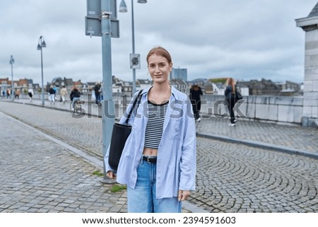 Young fashionable woman on bridge posing looking at camera, outdoor