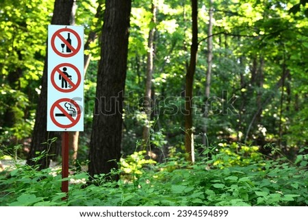 A wooden pole with prohibition signs in a park or forest. a safe public space in the green zone of the city.