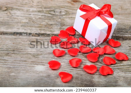 Holidays gift and red hearts on wooden background. Valentines day background.