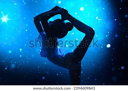 Silhouette of a girl gymnast doing an acrobatic stretching exercise. Blue background with snowflakes