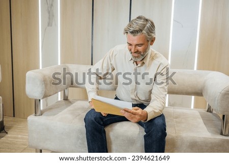 Excited mature male worker reading good news in paper letter get work promotion, smiling overjoyed man triumph receive pleasant paperwork correspondence Royalty-Free Stock Photo #2394621649