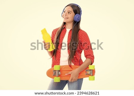 Fashion teenage lifestyle, beautiful teen girl with skateboard water bottle and headphones isolated on white studio background. Portrait of happy smiling teenage child girl.