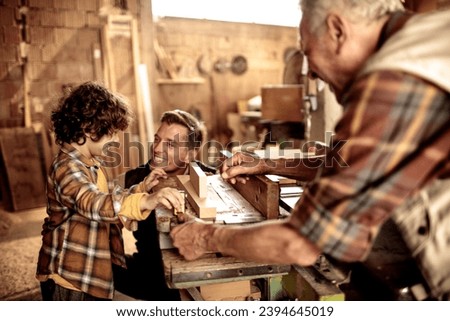 Young Boy Learns Woodworking Skills from His Elderly Grandfather and Father in a Workshop