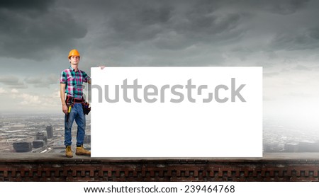 Young repairman with white blank banner. Place for text