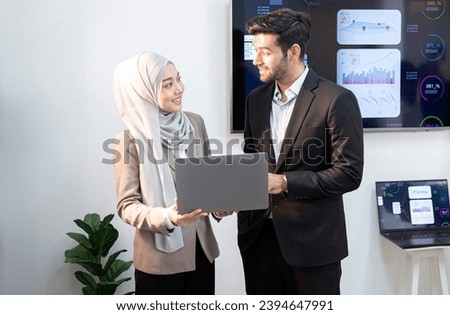 A young executive and a female employee stand and look at a notebook. for online business meetings of the company
