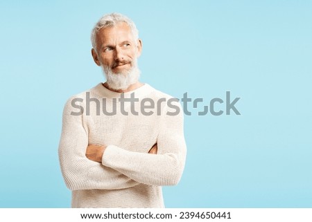 Portrait of handsome mature Scandinavian man wearing stylish sweater looking away, choosing something isolated on blue background, copy space. Shopping, store concept  Royalty-Free Stock Photo #2394650441