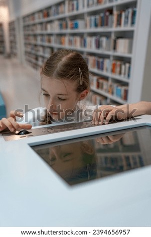 Interactive information search system in the library. A schoolgirl is in the library, looking for information on the computer. Royalty-Free Stock Photo #2394656957