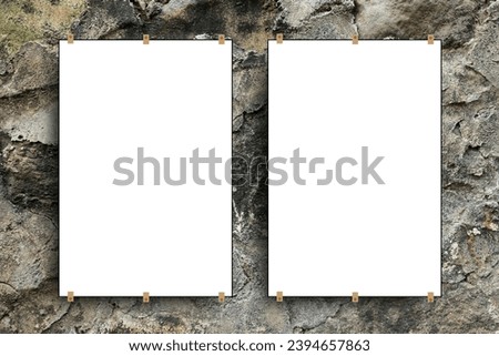 Close-up view of two paper sheet frames attached with drill nails on gray stone wall background