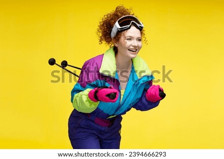 Smiling attractive woman, skier  wearing winter goggles, stylish overalls, looking away isolated on yellow background. Mountains vacation, winter resort, travel concept