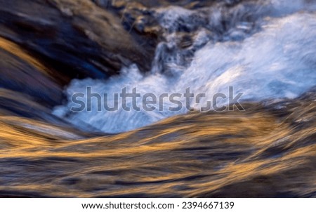 An abstract photo of flowing water in a creek at a slow shutter speed.