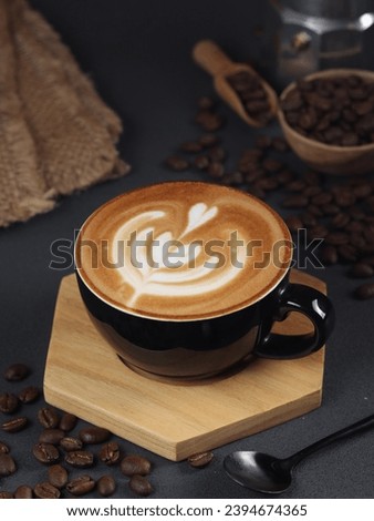 Side view of hot latte coffee with latte art in a bright black cup and saucer isolated on dark background with clipping path inside.
