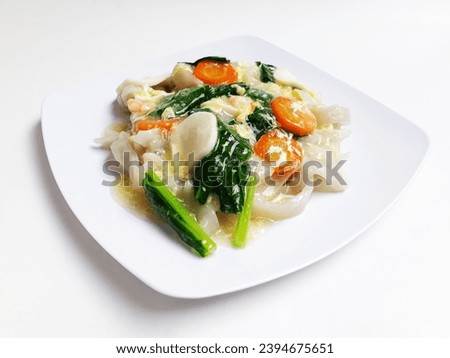 Kwetiau Siram is Chinese cuisine which is popular in Indonesia, cooked with vegetables, seafood, eggs and thick soup. Served on a white plate and isolated on a white background. Royalty-Free Stock Photo #2394675651