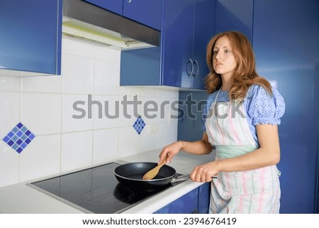 Blonde haired woman cooking in the kitchen (fear or surprise)