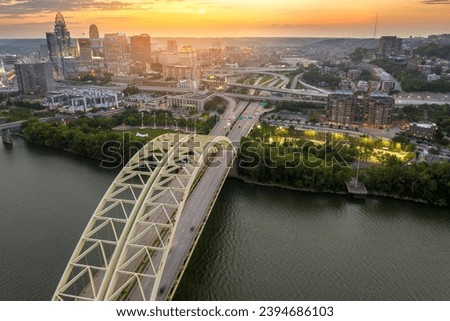 Cincinnati, Ohio with driving cars on Daniel Carter Beard Bridge highway near illuminated skyscraper buildings in downtown district in USA. American city with business financial district at sunset