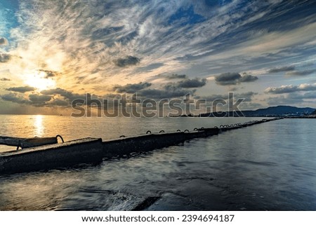 Colorful sunset on the Black Sea. Sea breakwaters. Sunset over the sea with waves. Seascape at sunset under a cloudy sky. Waves on the sea and dark clouds in the blue sky.