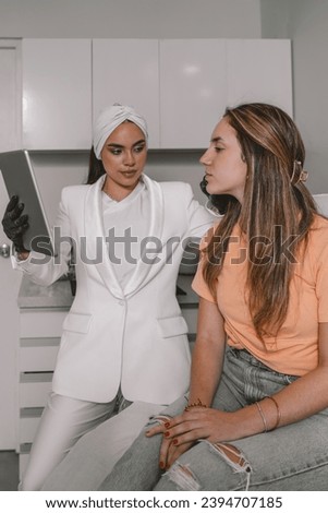 Doctor and woman using tablet in a medical beauty clinic before procedure of lips augmentation