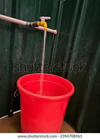 Old vintage faucet with drops of water filling a bucket. Water consumption concept