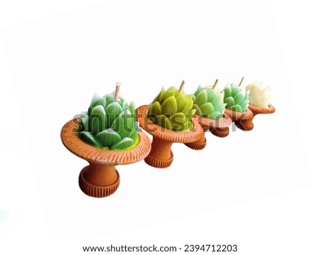 In the picture are five brown pottery trays. In the trays are five dark green and light green lotus candles placed in clay cups, arranged together, used to light fires at night during the Loy Krathong