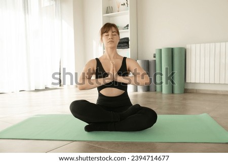 Yoga at home. Keep calm. Attractive young woman sitting on lotus position on floor with eyes closed. 