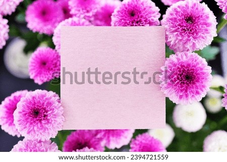 Mockup of a message card with an autumn image surrounded by white and pink round chrysanthemum flowers on a black background