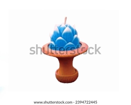 In the picture there is a brown clay tray. Inside the tray is a blue lotus candle with blue petals, white petals at the center and a white string for lighting.