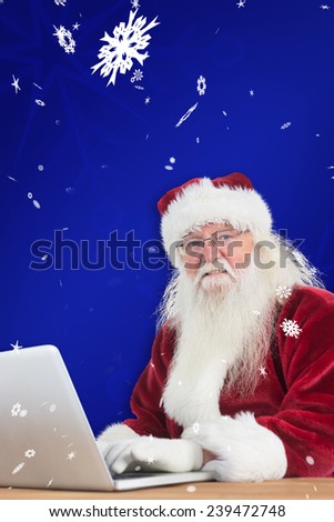 Santa surfs on the internet against blue snowflake background