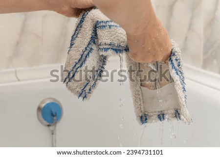 woman washing dirty mop head in bathtub. wet house cleaning. mop head Royalty-Free Stock Photo #2394731101