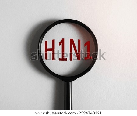 Magnifying glass focused on text H1N1 influenza virus serotype A, swine flu. Royalty-Free Stock Photo #2394740321