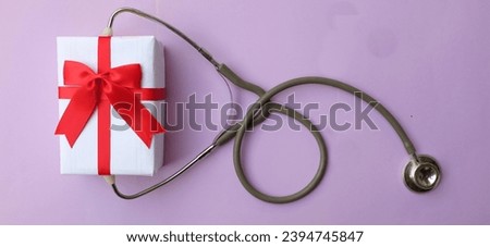 medical stethoscope with gift box isolated on a purple pastel background. concept christmas and new year.horizontal photo