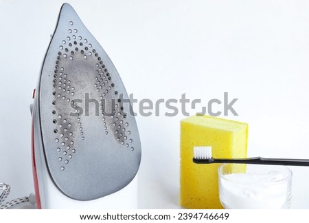Burnt dirty electric flat iron. Clean an base surface with Baking soda, sponge. burnt iron for ironing. Cleaning the iron from carbon deposits Royalty-Free Stock Photo #2394746649