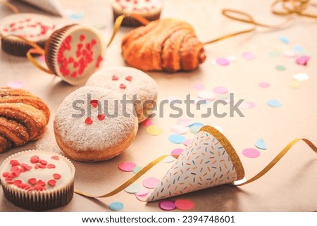 Berliner, cinnamon rolls and cupcakes for carnival and party. German Krapfen or donuts with streamers and confetti. Colorful carnival or birthday image