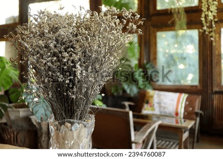 Close up of glass jar with dried flowers decoration in cafe and drinking coffee. Decorative statice flowers in a vase