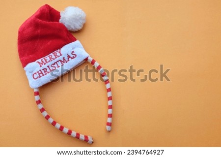 Beautiful headband 
 Decorative red Santa Hat isolate on a orange backdrop.
concept of joyful Christmas party,New year is coming soon, festive season decoration with Christmas elements