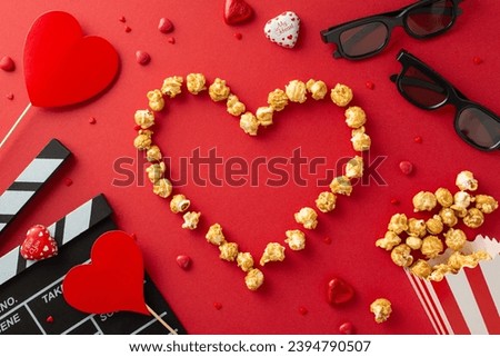Romantic Film Night: top view of clapper, 3D glasses, popcorn layed out in shape of heart, chocolate candies, heart-shaped decor on red backdrop— perfect blend for Saint Valentine's Day movie premiere Royalty-Free Stock Photo #2394790507