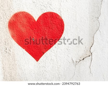 Red love heart spray painted on wall background. One red heart painted on concrete fence backdrop. Happy Valentines day. 14th february. Royalty-Free Stock Photo #2394792763