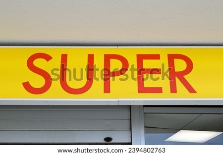 Yellow Plastic Sign 'Super' with Red Lettering above Shop Entrance 