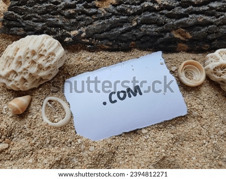 The text .com on the beach sand background.