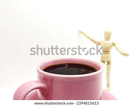 The black coffee in a soft pink cup with a wooden mannequin as a model has a "need more coffee" concept photographed on an isolated white background