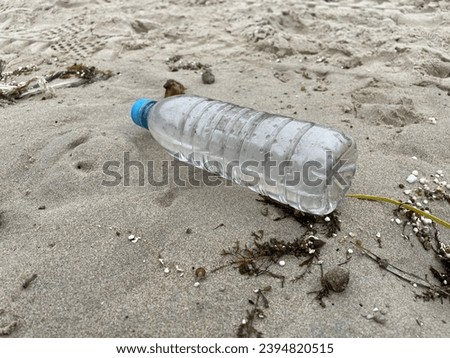 exterior top view photo of a plastic bottle of liquid water stranded on the sand of a beach as a trash rubbish gabbage in nature making plastic pollution that pollute the sea or the ocean