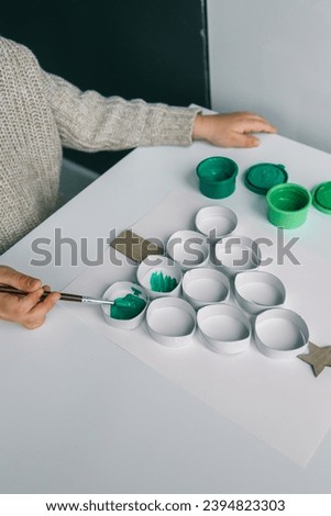 A child draws a Christmas tree. Ideas for drawing with bright colors. Drawing children on a white background. A little girl draws with paint and brushes. The concept of children's development.
