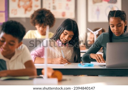 Secondary Or High School Students Studying Wind Turbines In Science Class With Teacher In Background Royalty-Free Stock Photo #2394840147