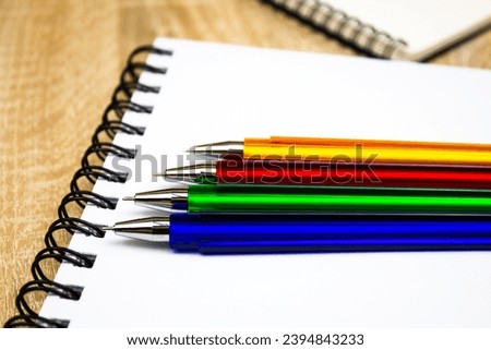 Ballpoint pens. Choice of handles. Colored pens. Ink pens for writing. Pens lie on the notepad page. Office stationery concept. Royalty-Free Stock Photo #2394843233