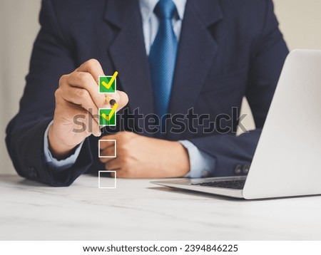 Quality control assurance of ISO concept. A businessman in a suit using an electronic pen to tick the correct sign mark in an online document checklist while sitting at the desk in the office