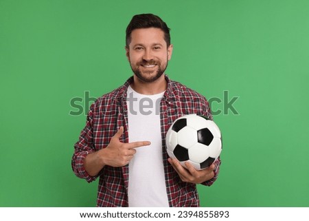 Happy sports fan with ball on green background